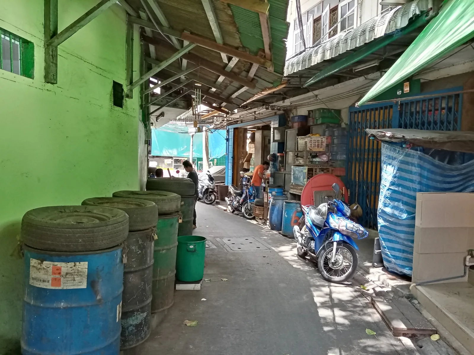 Narrow lane with workshops, barrels and a motorcycle in Talat Noi’s Sieng Kong area