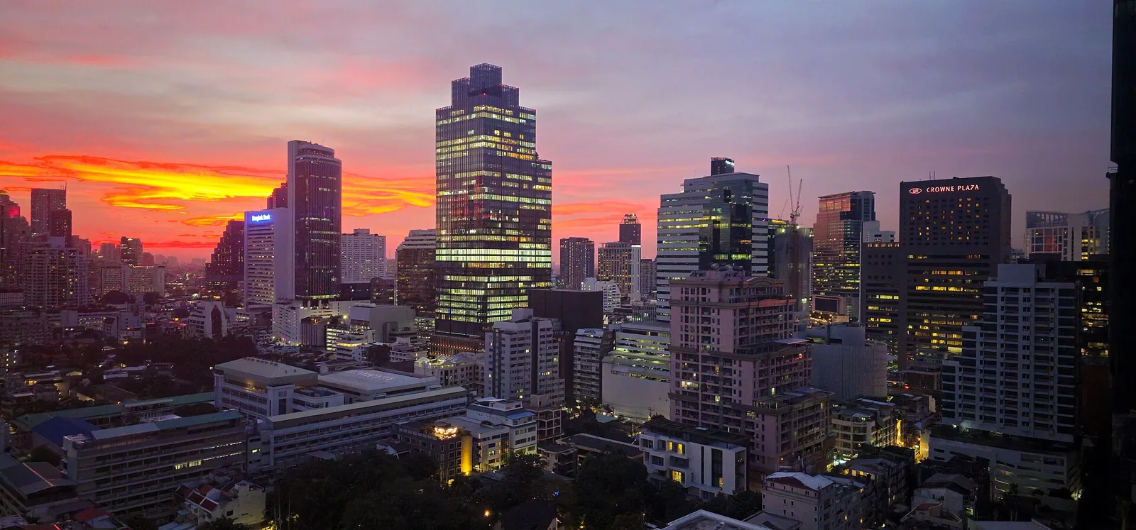 Bangkok skyline with high-rise buildings beneath a pink and orange sunset