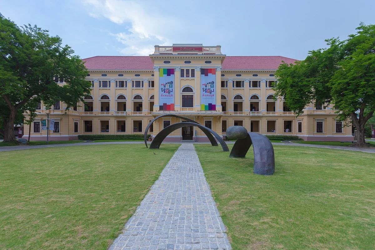 Pale yellow Museum Siam building and green lawn beneath a blue sky